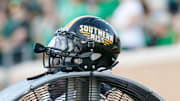 Oct 18, 2014; Denton, TX, USA; A Southern Miss Golden Eagles helmet atop a fan during the first quarter at Apogee Stadium. Southern Miss won 30-20. Mandatory Credit: Ray Carlin-Imagn Images